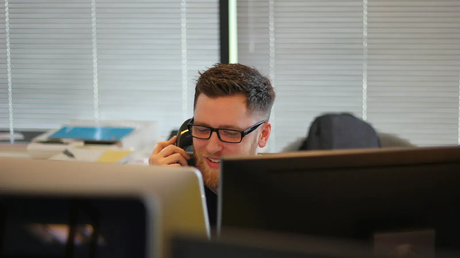 Person telefoniert am Schreibtisch und macht Notizen