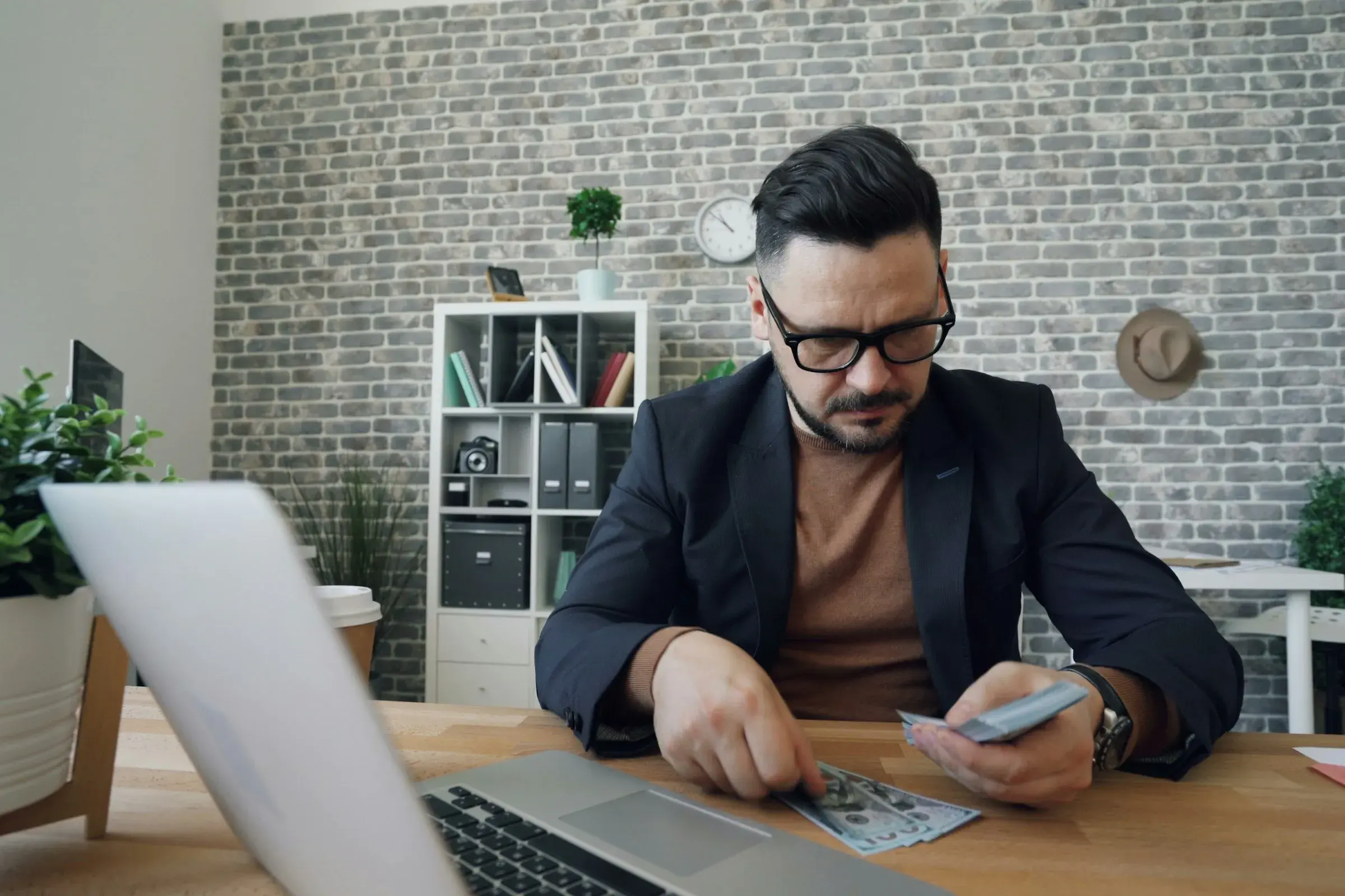 Mann sitzt am Tisch vor einem Laptop