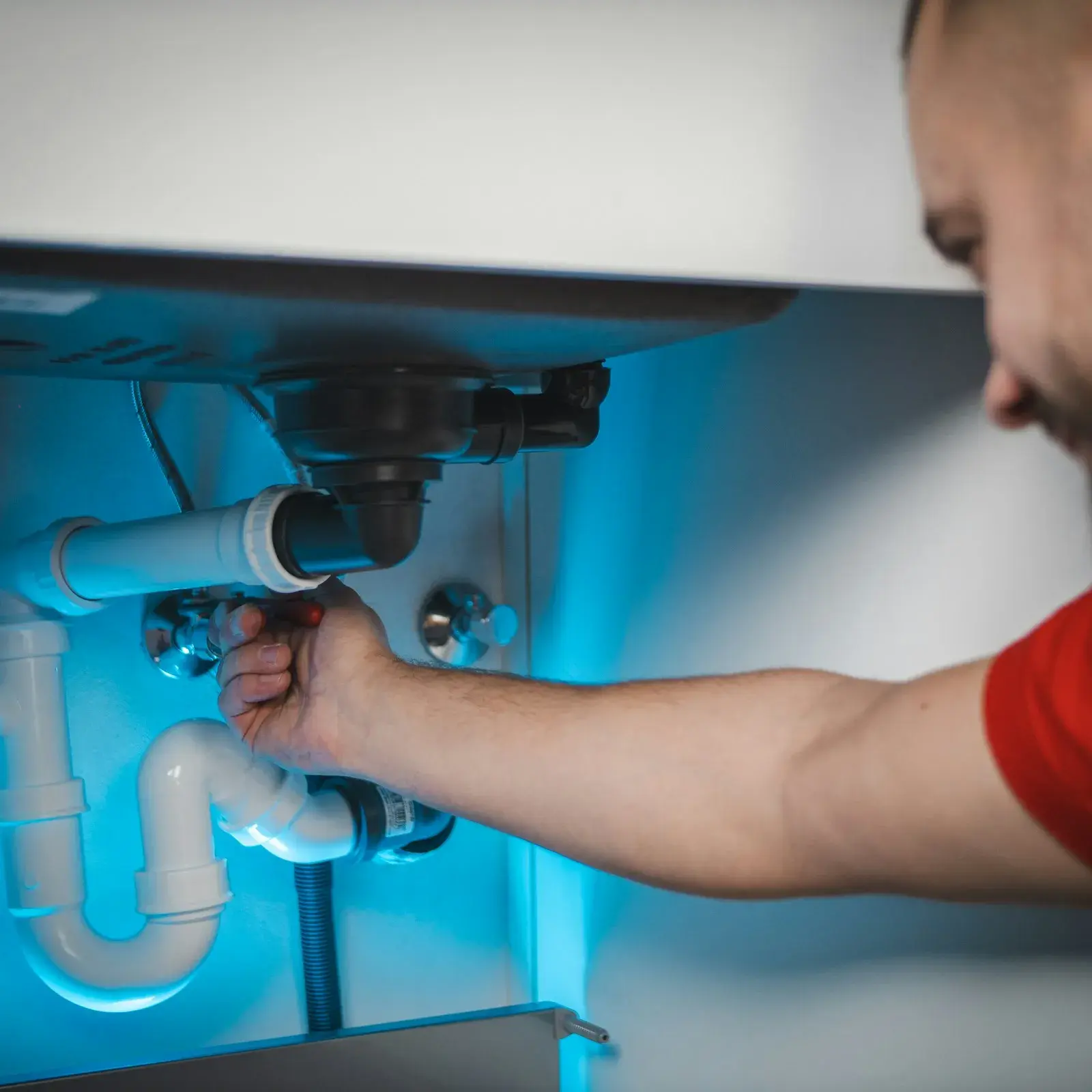 Mann arbeitet an einer Leitung in der Wand